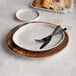 An American Metalcraft faux acacia melamine charger with a fork and knife on it.