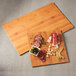 An American Metalcraft bamboo melamine serving board with meat and vegetables on it.