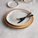 An American Metalcraft faux rustic wood melamine charger plate with a fork and knife on it.