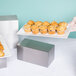 A stainless steel rectangular riser holding a white plate of muffins.
