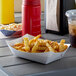A white paper food tray with french fries and a drink on a table.