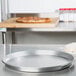 An American Metalcraft aluminum pizza pan on a counter with a pizza on it.