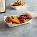 Two white #500 customizable paper food trays filled with fried food and sauce.