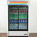 A white True refrigerated glass door merchandiser filled with soda bottles.