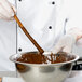 A chef stirring Ghirardelli dark chocolate in a bowl.