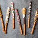 A chocolate covered pretzel stick with orange and brown sprinkles.