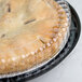 A black pie in a plastic container with a clear low dome lid on a counter.