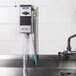 A Dema ProFill chemical dispenser attached to a metal sink.