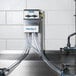 A Dema ProFill 2 multi compartment sink chemical dispenser pump with pipes attached to it.