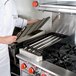 A chef using a FMP Add-On Charbroiler in a commercial kitchen.