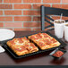 A rectangular pepperoni pizza on a black HS Inc. Pizza Pleezer tray with two cups of iced tea.