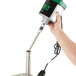 A hand using a green and black Noble Products drive shaft to clean a metal surface.