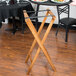 A Lancaster Table & Seating wooden folding tray stand with plates on it.