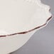 A white stoneware bowl with brown rim.