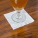 A glass of beer on a white Choice cocktail napkin.