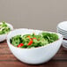 A close up of a white Osslo melamine bowl filled with salad.