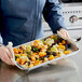 A hand holding a Chicago Metallic aluminized steel jelly roll pan with vegetables.