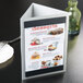 A Menu Solutions brushed aluminum triple view table tent with a menu on a white table.