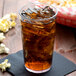 A Cambro clear plastic tumbler of ice tea with ice and popcorn.