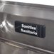 A Tablecraft Sanitario sign on a metal surface.