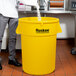 A person standing next to a yellow Continental Huskee trash can.