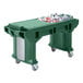 A green Cambro Versa work table with standard casters holding a green plastic bin filled with bottles.