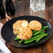 A 10 Strawberry Street Wazee Matte black stoneware dinner plate with two fish cakes and green beans.