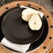 A black 10 Strawberry Street Wazee Matte stoneware salad plate with a pear on it.