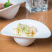 A close up of a 10 Strawberry Street Somba white porcelain bowl filled with noodles and soup.