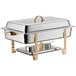 A stainless steel Choice Deluxe chafer with gold accents on a table outdoors.