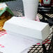 A white paper sandwich clamshell container on a table.