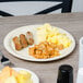 A Carlisle tan melamine plate with food on a table.