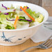 A bowl of salad with lettuce and carrots in a Thunder Group Blue Bamboo melamine bowl on a table.