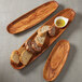 An American Metalcraft oblong olive wood boat with bread slices and sauce on a wooden tray.
