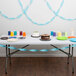 A table with a cake and cups with Bermuda Blue Streamers on it.