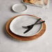 An American Metalcraft faux olive wood melamine charger with a fork and knife on it.