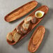 An American Metalcraft oblong wooden boat with bread slices and sauce on a wooden platter.