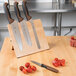 A Mercer Culinary Millennia knife set on a wooden magnetic board with tomatoes.