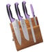 A Mercer Culinary Millennia Colors knife set with purple handles on a wooden stand.