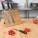A Mercer Culinary Genesis bamboo cutting board with knives on it.