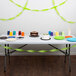 A table with a cake and cups on it with Fresh Lime Green Streamer Paper decorating the table.