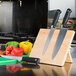 A Mercer Culinary rubberwood knife rack holding three knives.