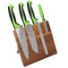 A Mercer Culinary Millennia Colors® knife set with green handles on an acacia magnetic board.