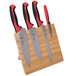 A Mercer Culinary Millennia Colors® knife set with red handles on a bamboo magnetic board.