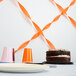 A cake on a table with orange streamers on the table.