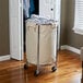 A Chrome laundry hamper with a white bag on a metal stand.
