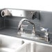 A close-up of a stainless steel sink with two faucets on a counter.