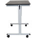 A grey Luxor stand up desk with wheels and a black oak desktop.