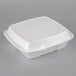 A white Dart foam three-compartment takeout container with a perforated lid.