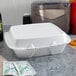 A white Dart foam take out container with a lid on a table with condiments.